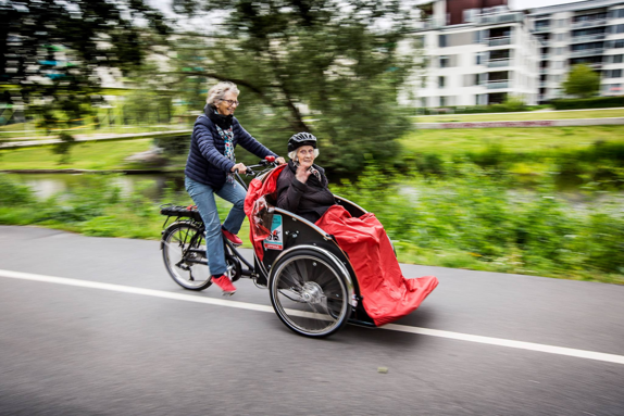 En volontär cyklar tillsammans med en passagerare i framvagnen.