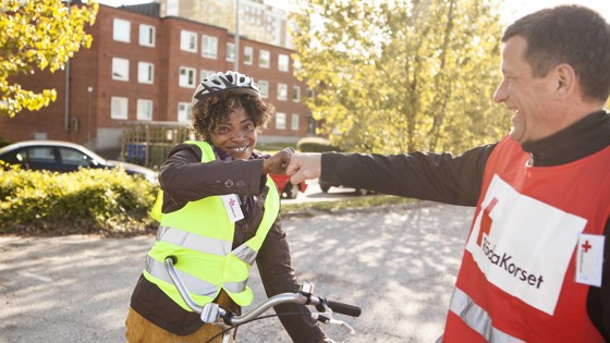 Rödakorsare hälsar på ungdom i cykelhjälm